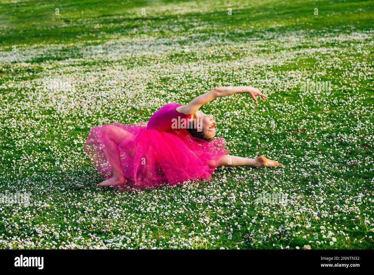 Ballerina doing splits on lawn with flowers, Battle Point Park, Bainbridge Island, Washington, USA Stock Photo