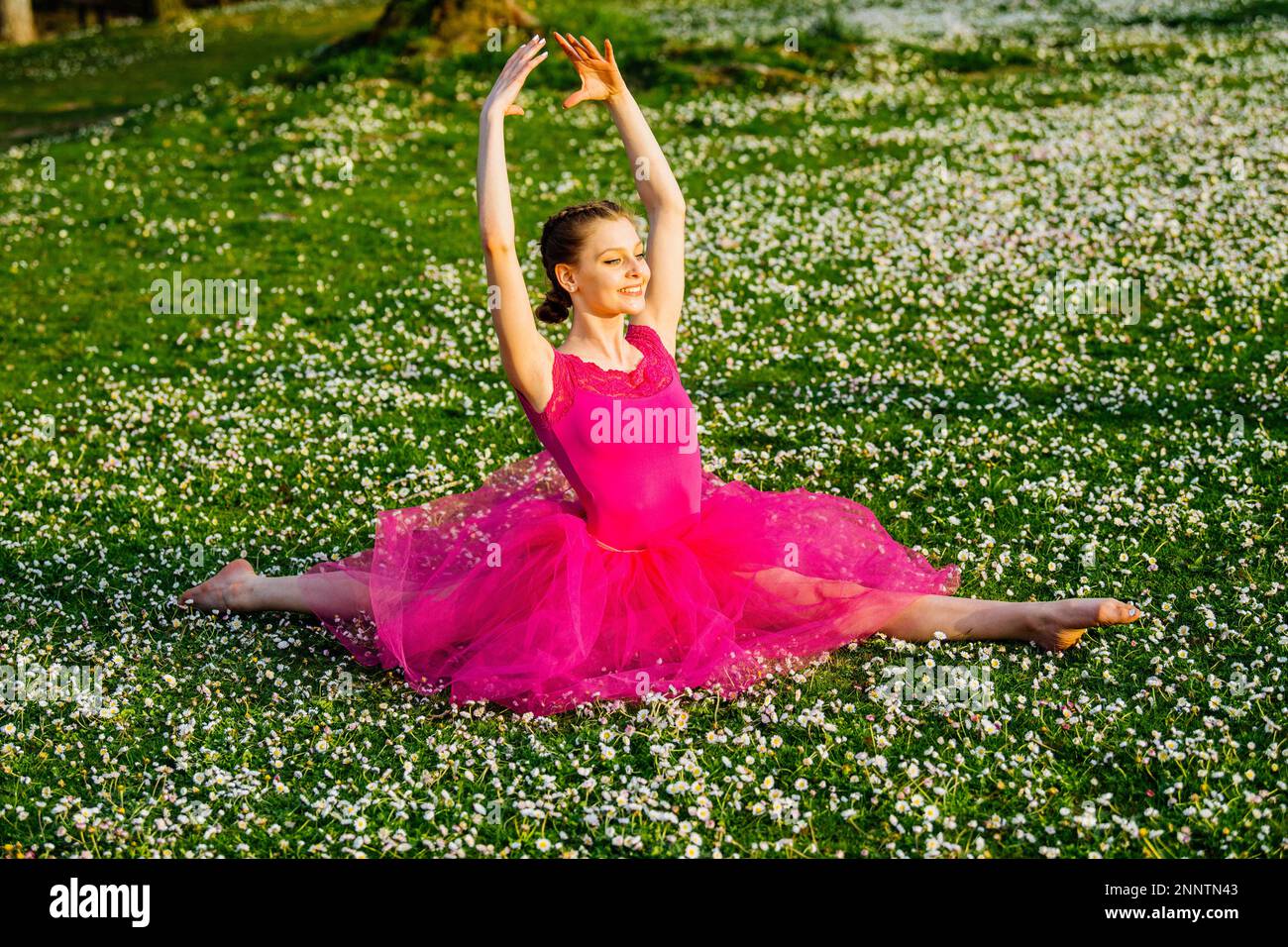 Ballerina doing splits on lawn with flowers, Battle Point Park, Bainbridge Island, Washington, USA Stock Photo