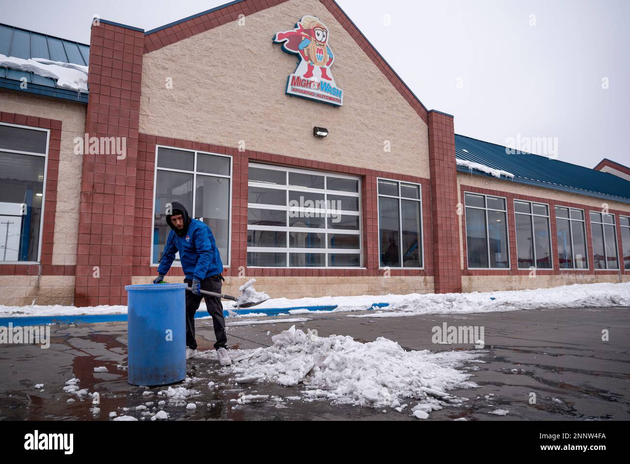 Mighty Wash employee Cesar Zapata fills a barrel with snow and ice as