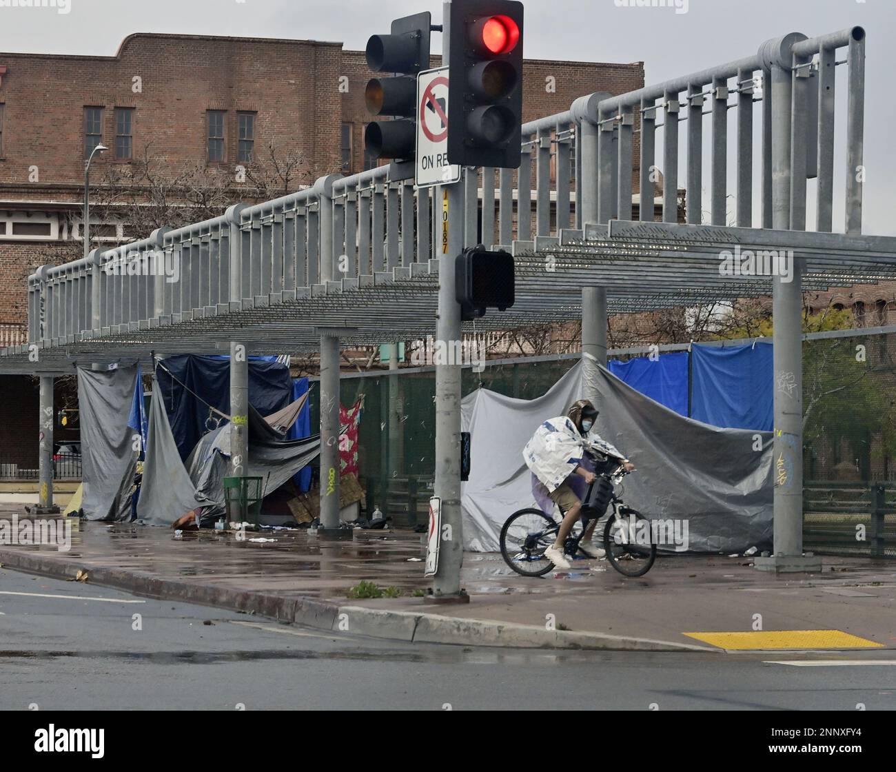 A Homeless Man Rides His Bike Past A Homeless Encampment Over The 101 