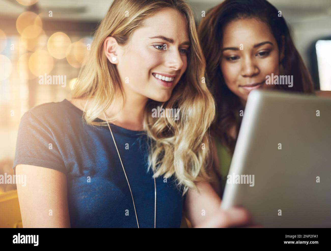 Sharing some online time. girlfriends sharing something on a digital tablet while sitting in a cafe. Stock Photo