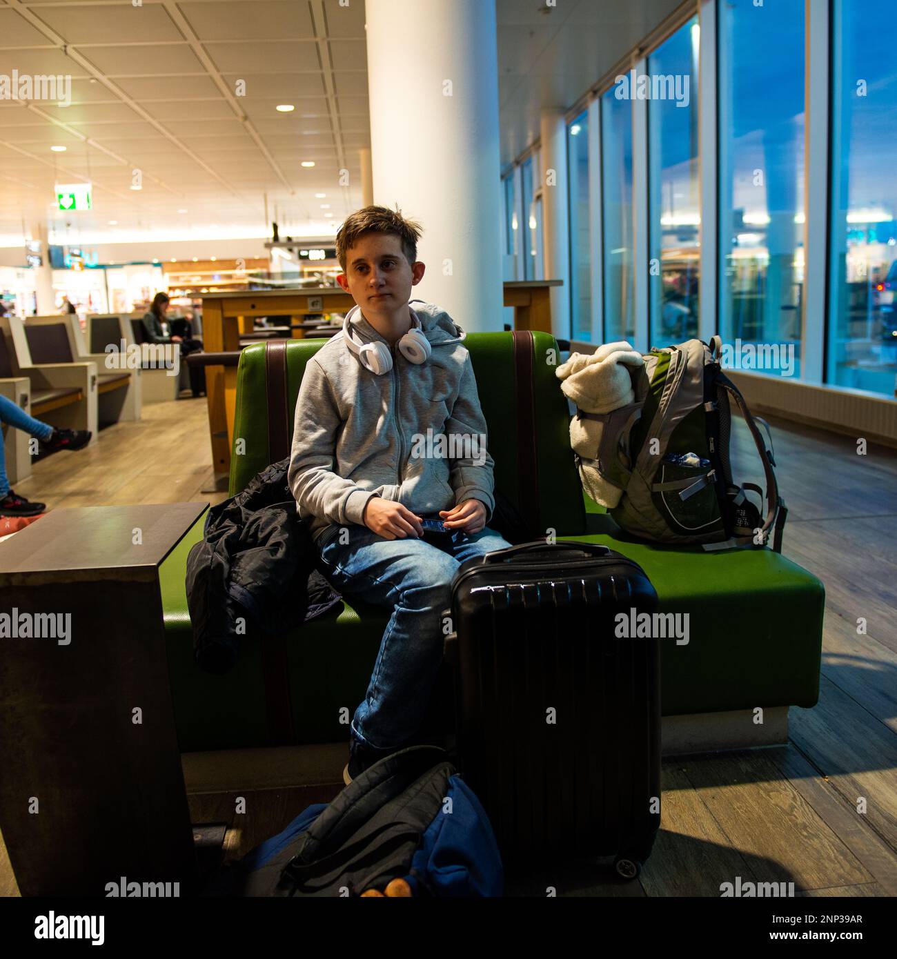 A young man waits for his flight to be announced at an airport Stock Photo