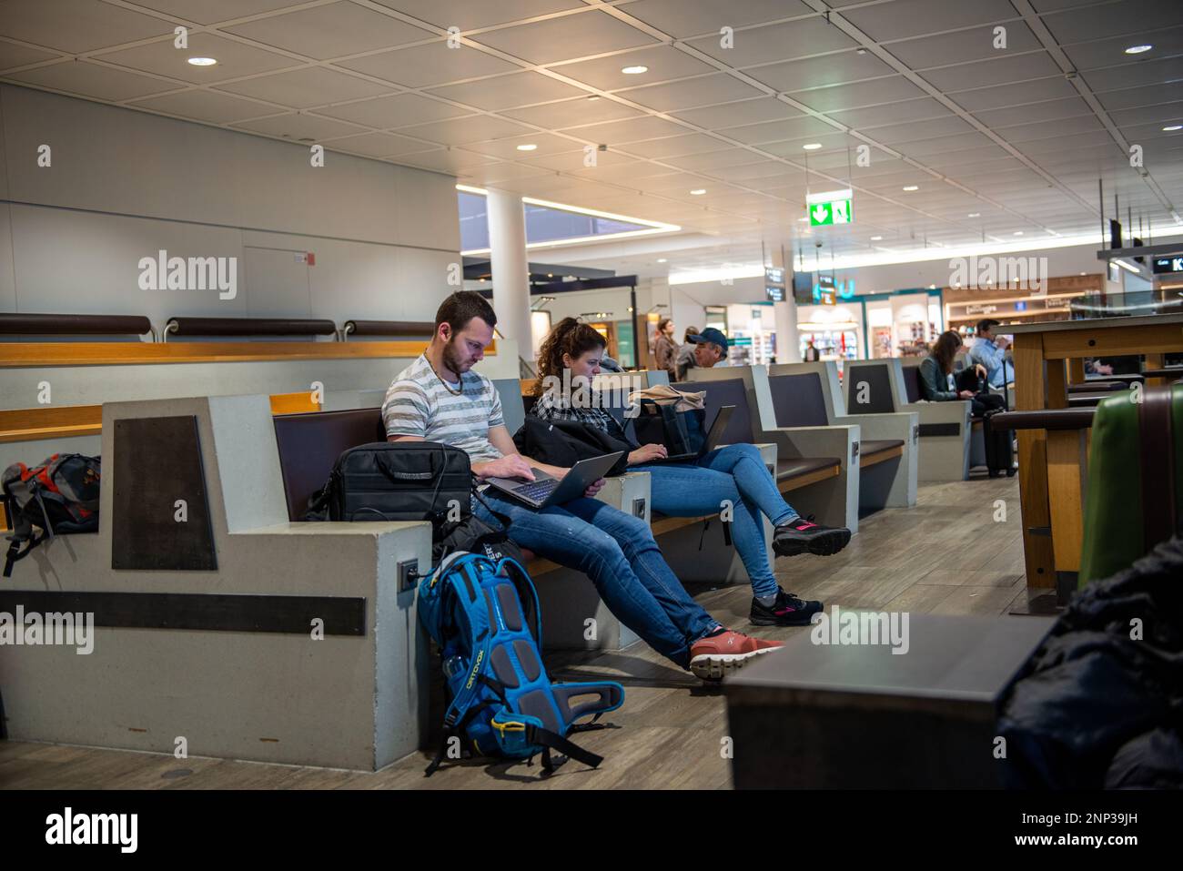 Munich,Germany- February 20,2023: Two people look at their notebook computers while waiting for their flight to be announced. Stock Photo