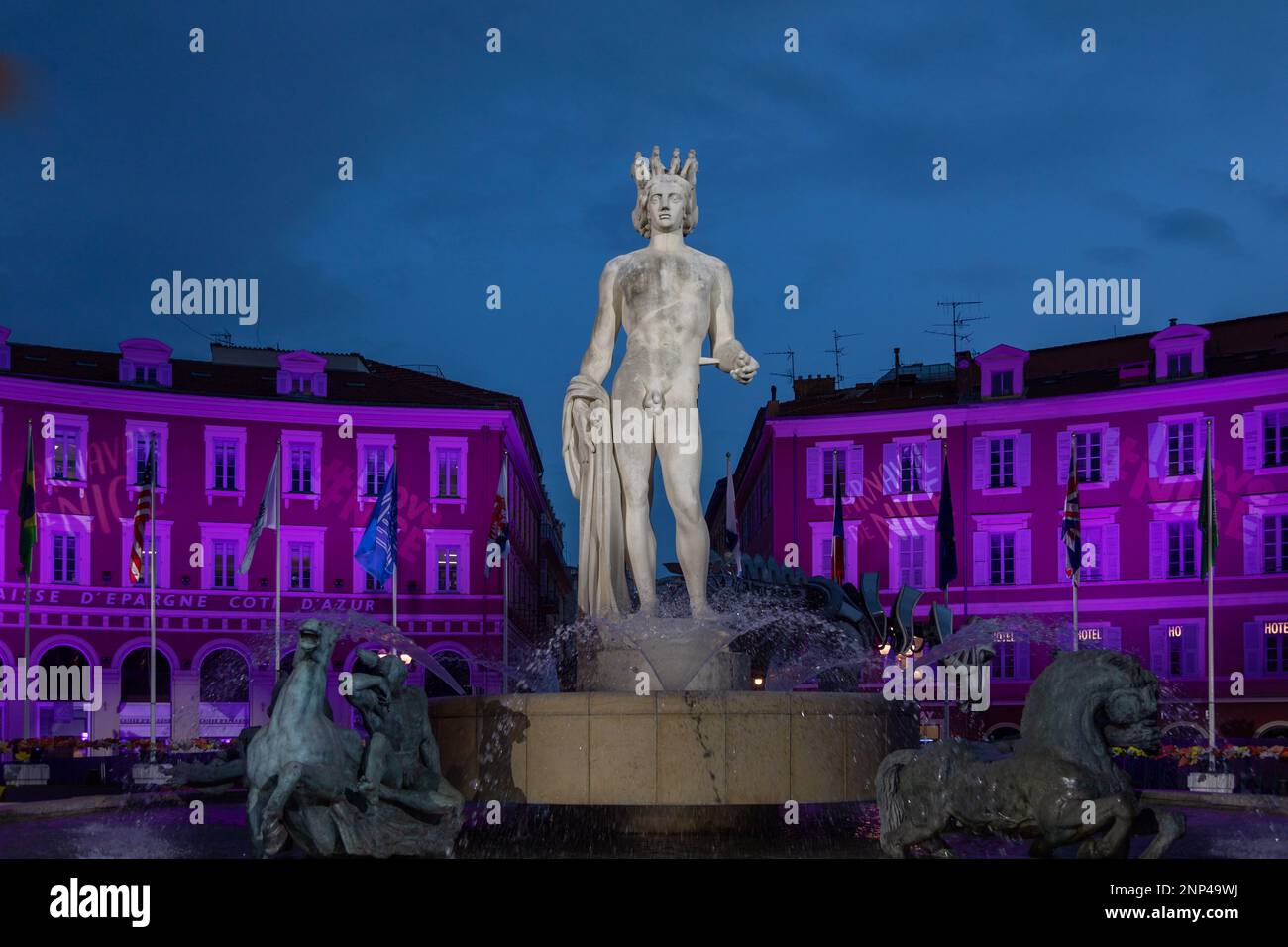 Landmark bronze sculpture of Greek god Apollo, Fontaine du Soleil,  Place Massena, a large square in Nice, France, in the evening, lite up for the Car Stock Photo