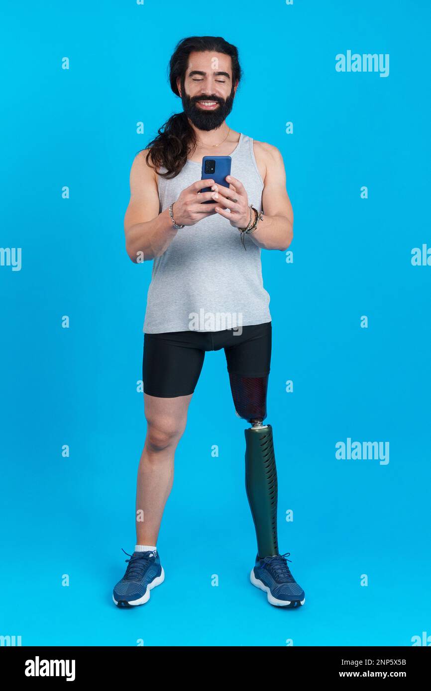 Distracted sportive man with a leg prosthesis using a mobile Stock Photo