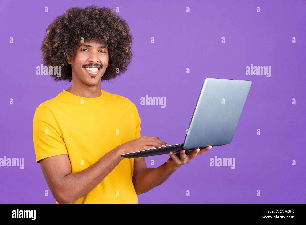 Smiley african man standing and using a laptop Stock Photo