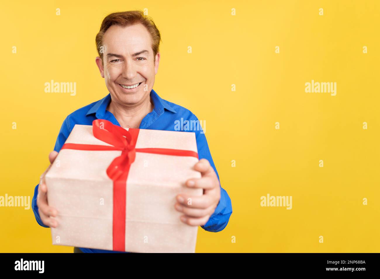 Mature man looking at camera happily holding a present Stock Photo