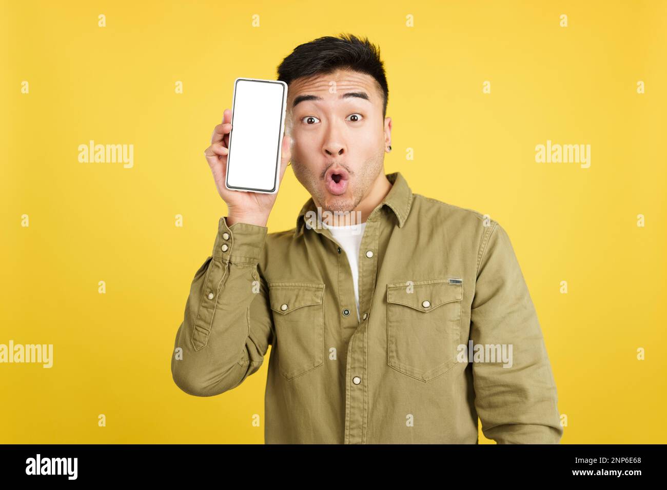 Surprised chinese man holding a mobile with a blank screen Stock Photo