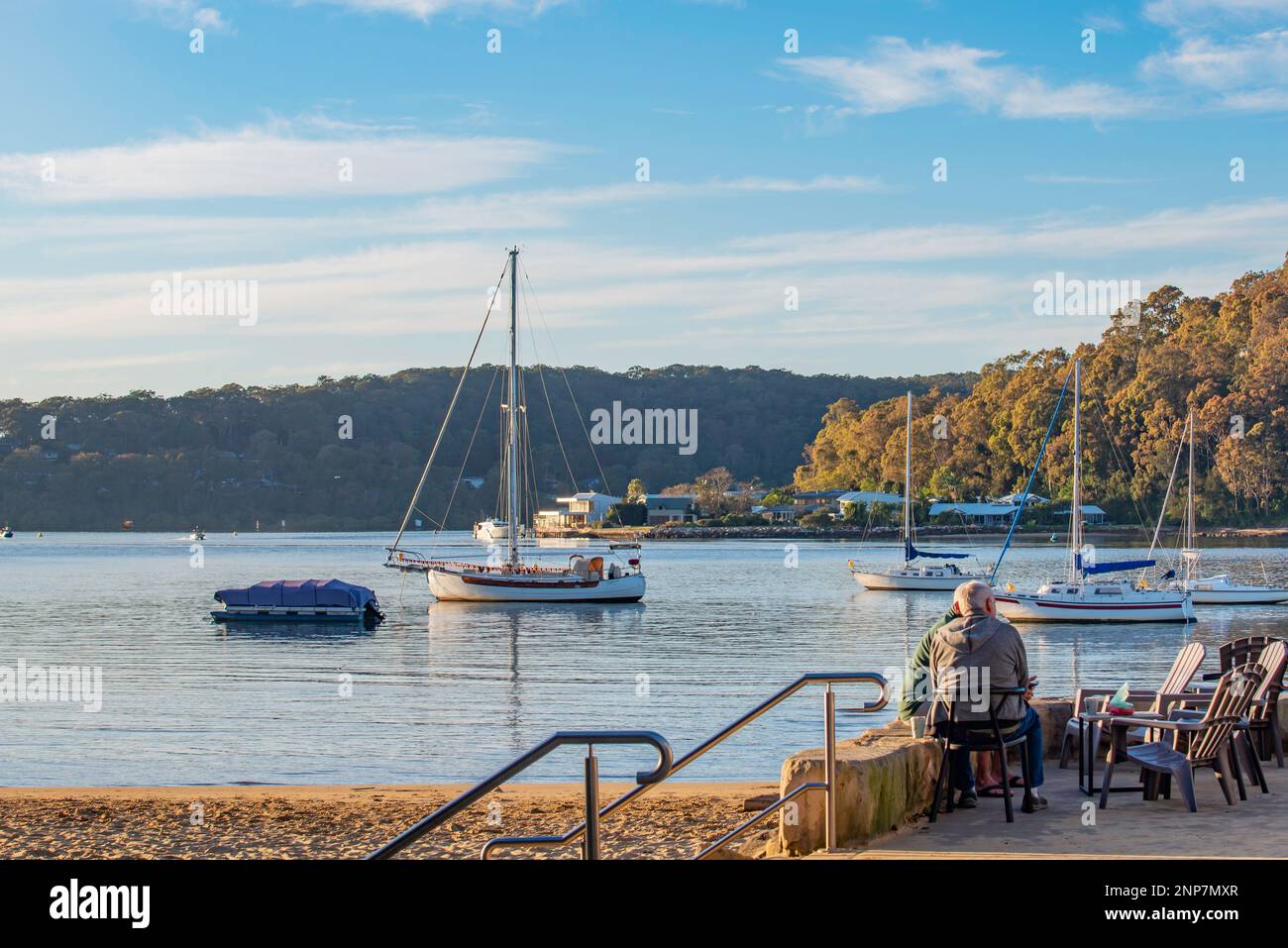 People enjoying coffee beside the water in the early morning sunshine at Ettalong Beach on the New South Wales Central Coast in Australia Stock Photo
