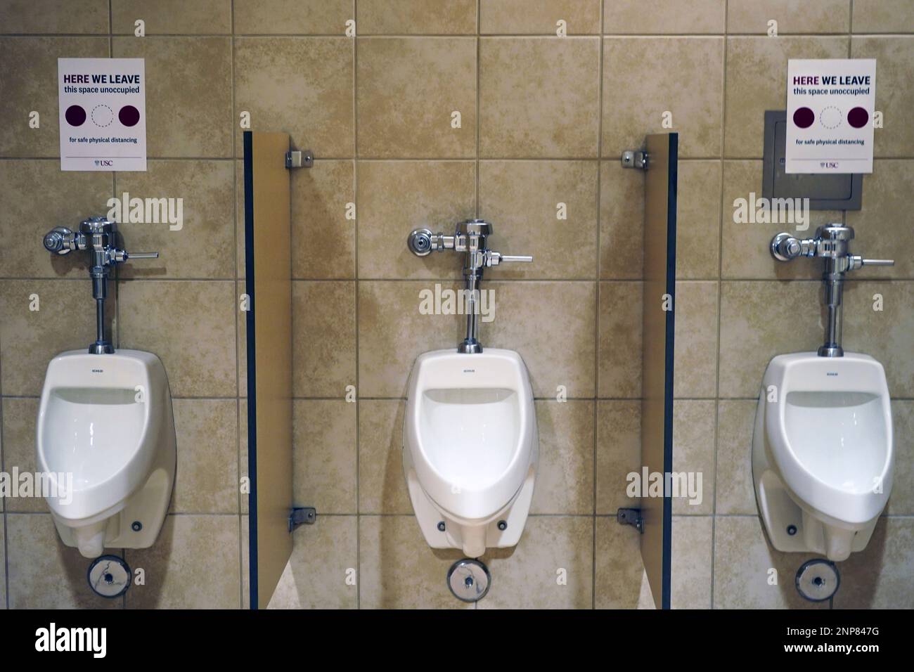 Social distance signs above urinals in the men's restroom at the Galen