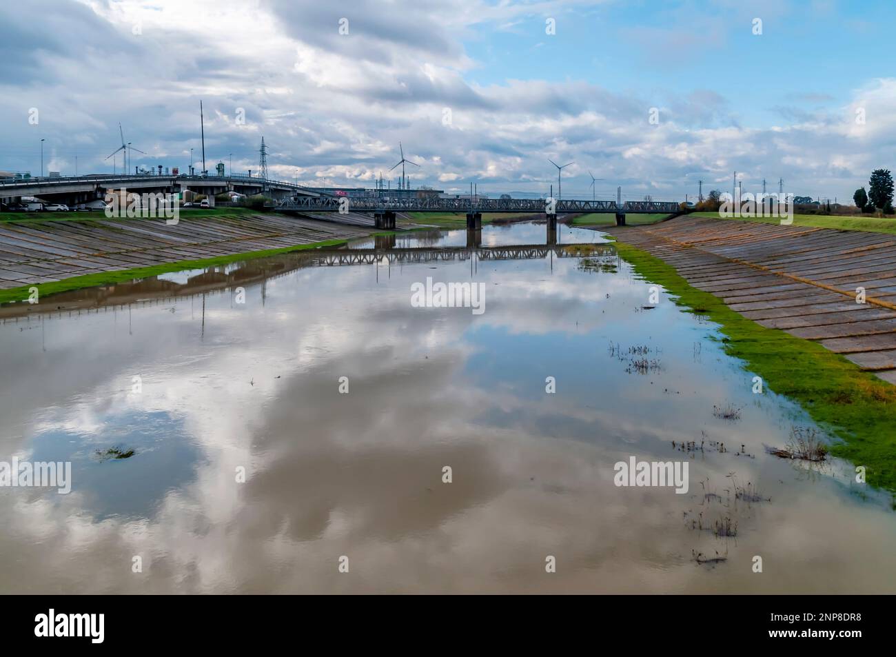 The industrial area and the railway are reflected in the water of the spillway in Pontedera, Pisa, Italy Stock Photo