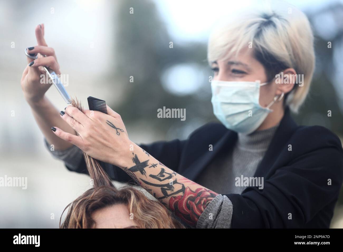 A hairdresser cuts the hair of a woman during a rally in front of the Congress of Deputies in