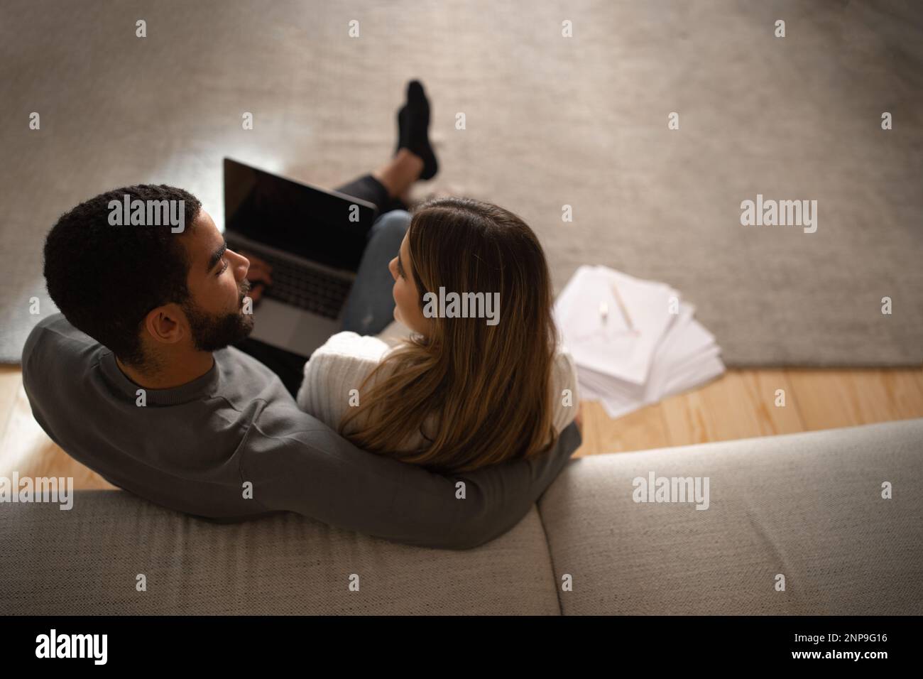 Young arabic male hug and look at european woman typing on computer ...