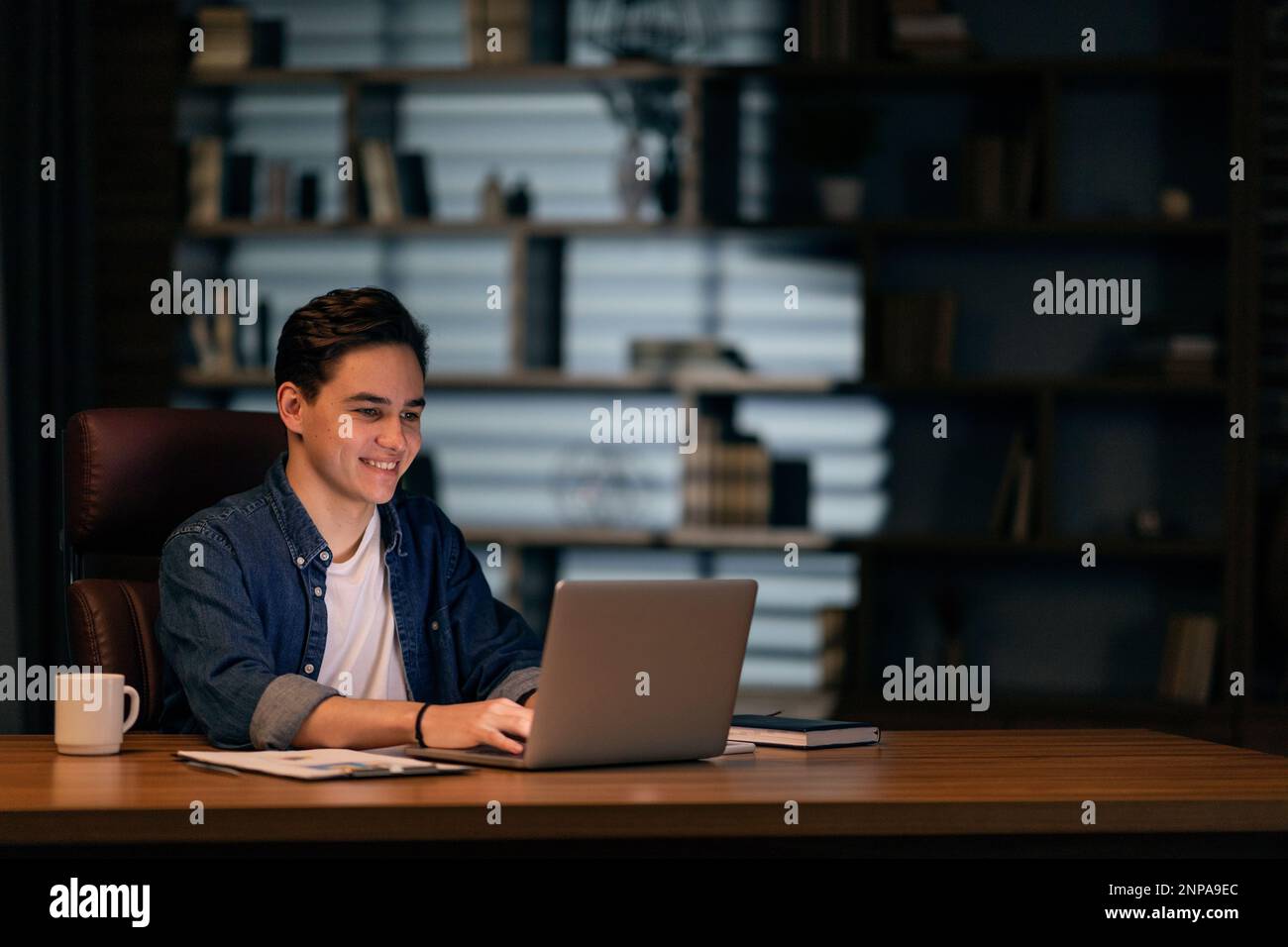 Young happy IT specialist working on laptop at office Stock Photo