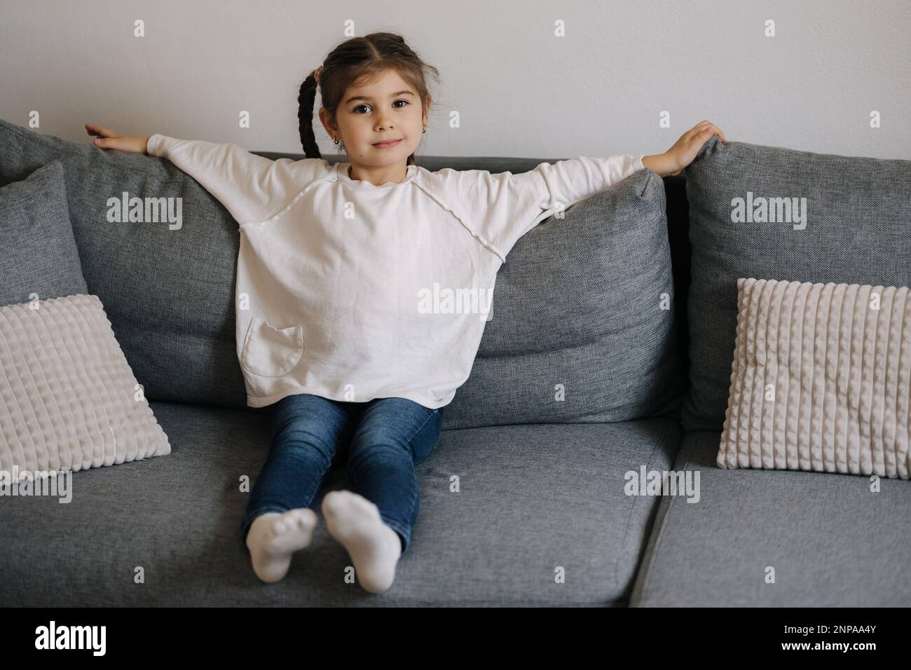 Cute little girl sitting on sofa at home. Home mood Stock Photo - Alamy