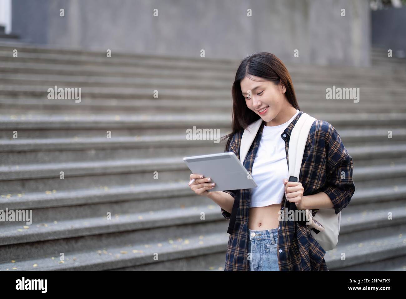 Asian female college student with her laptop in front of the campus ...