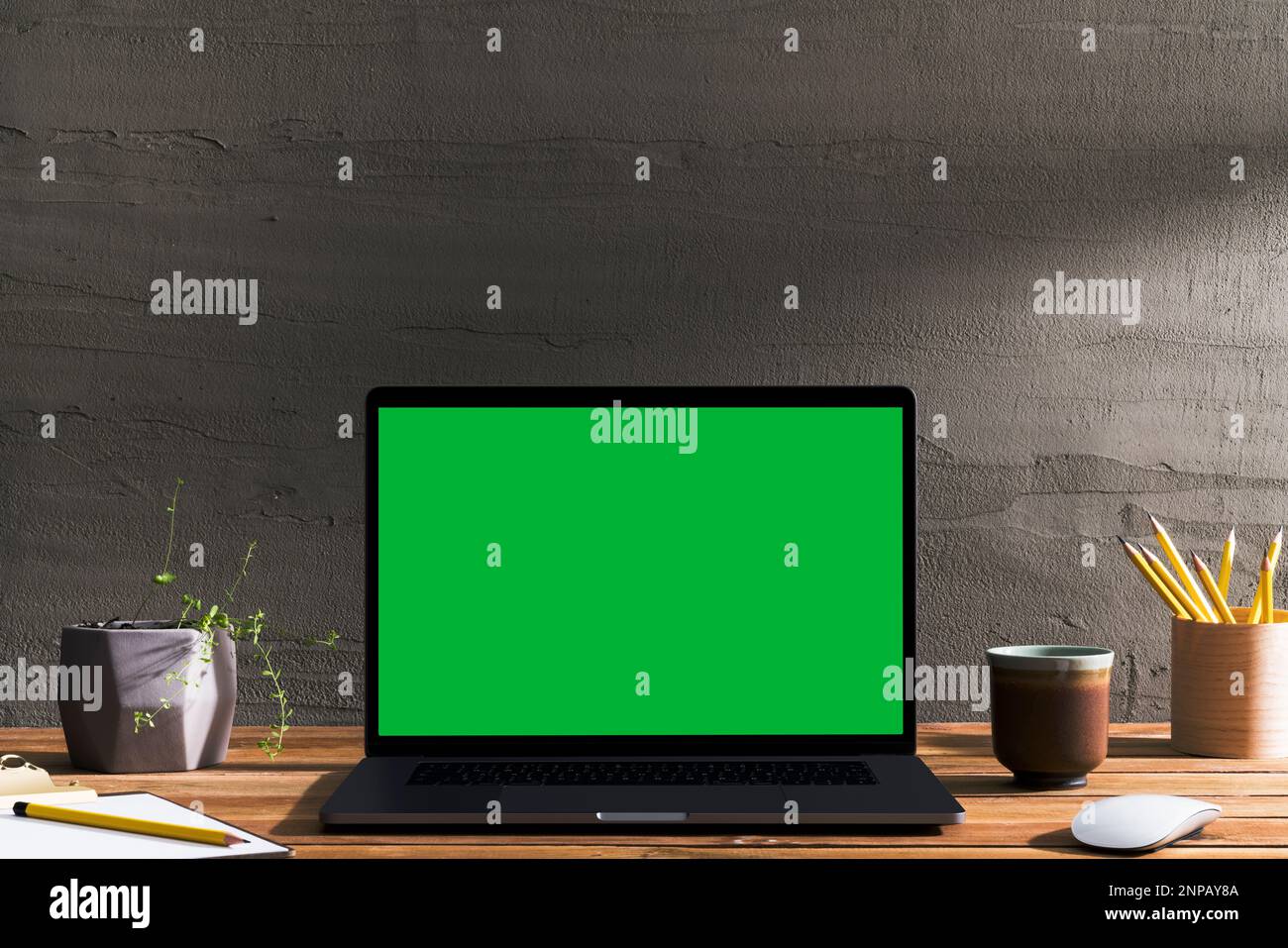 Chroma key green screen laptop on wooden table in front of concrete