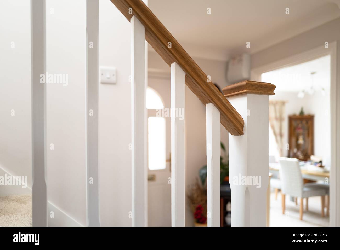 Shallow focus of a newly installed wooden banister seen near a porch and open dining room. Located at a show home. Stock Photo