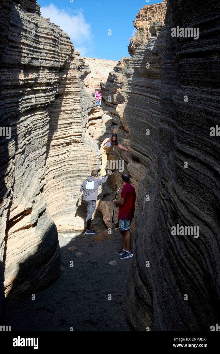 tourists walking inside layers of Ladera Del volcan Las Grietas Lanzarote, Canary Islands, Spain volcanic rock formations caused by erosion Stock Photo