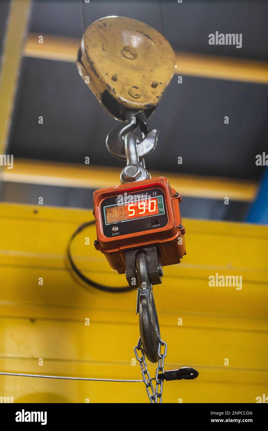 Huge industrial scales in a factory suspended from a crane Stock Photo