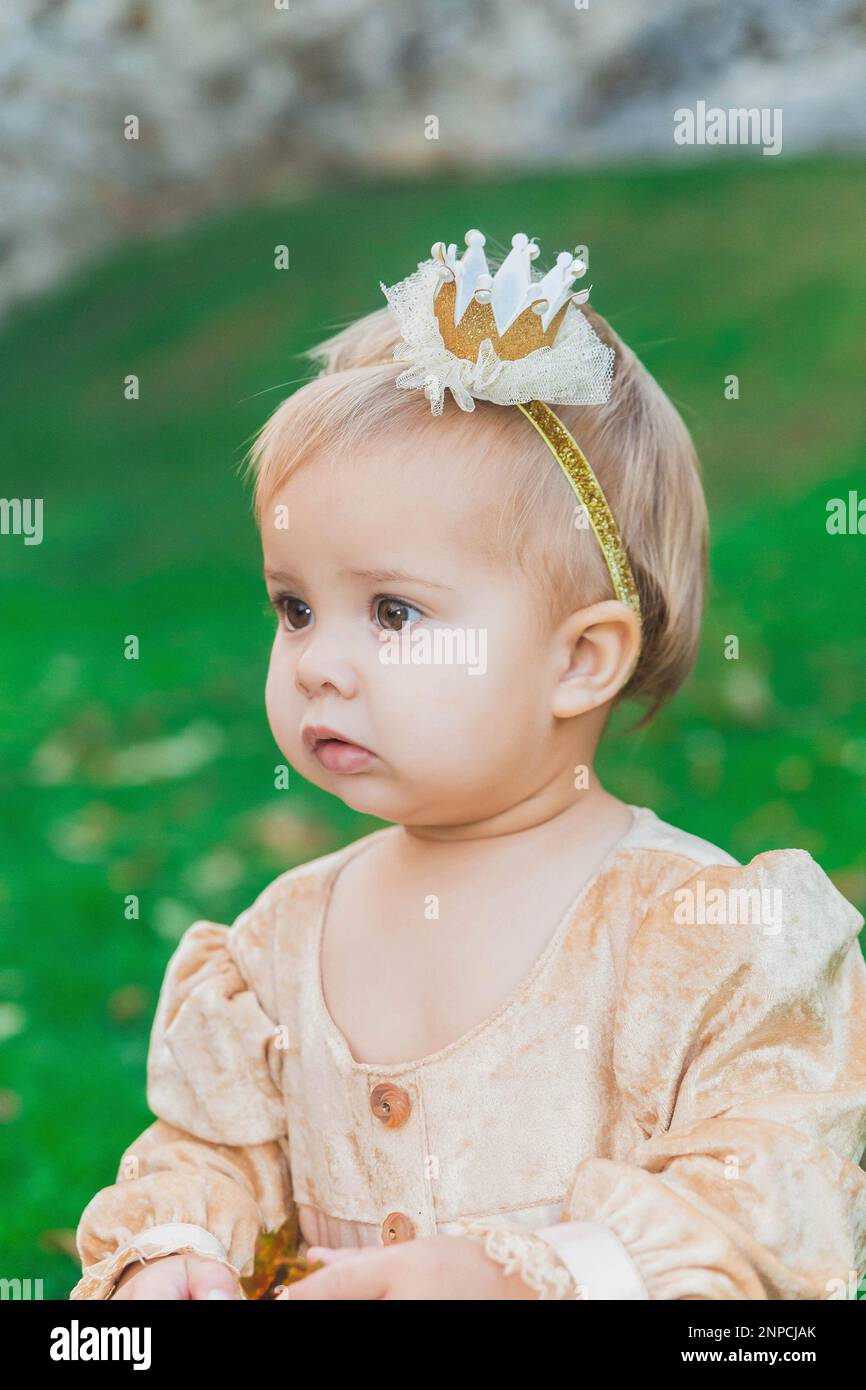 charming baby in princess costume walks near the castle at sunset Stock Photo