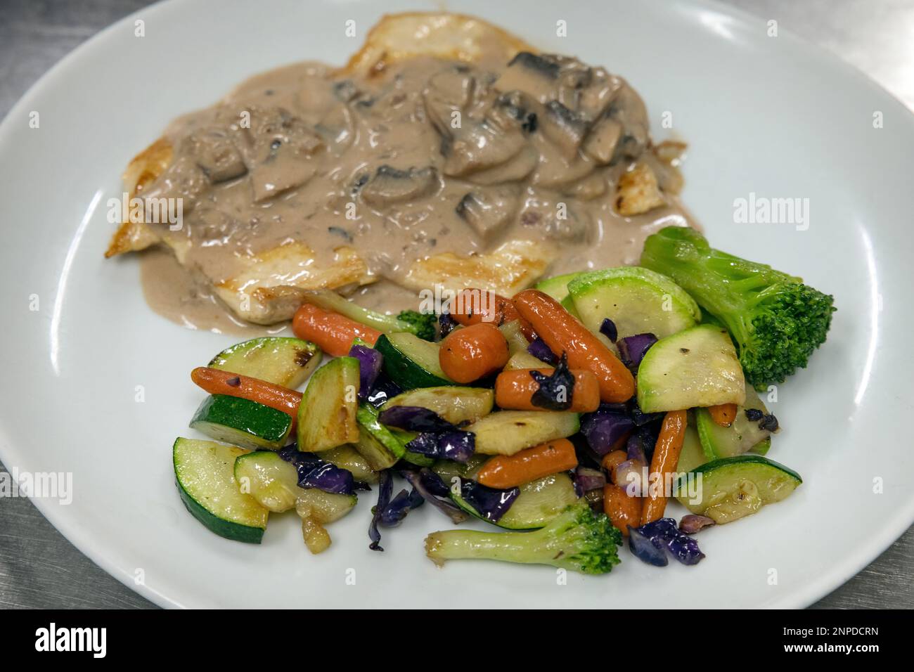 Tasty chicken with mushroom sauce and grilled vegetables aside ready to be consumed, appetizing dish offering a diverse range of veggies and a protein Stock Photo