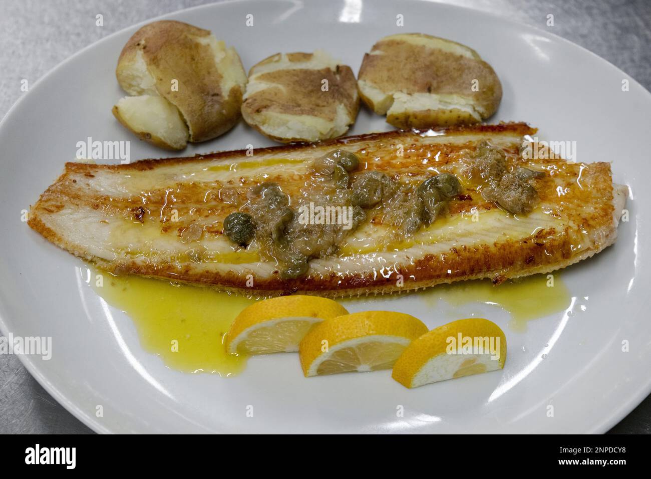 Sole fish with Canarian potatoes and capers sauce, seafood dish with a tasty flavorsome fish, papas arrugadas, a type of small potatoes and capers Stock Photo
