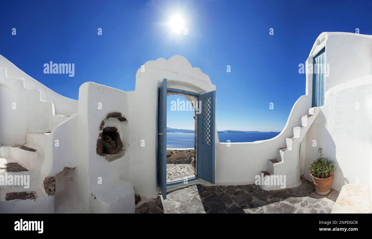 A panoramic view of the caldera of Santorini from a traditional cave house and doorway. Stock Photo