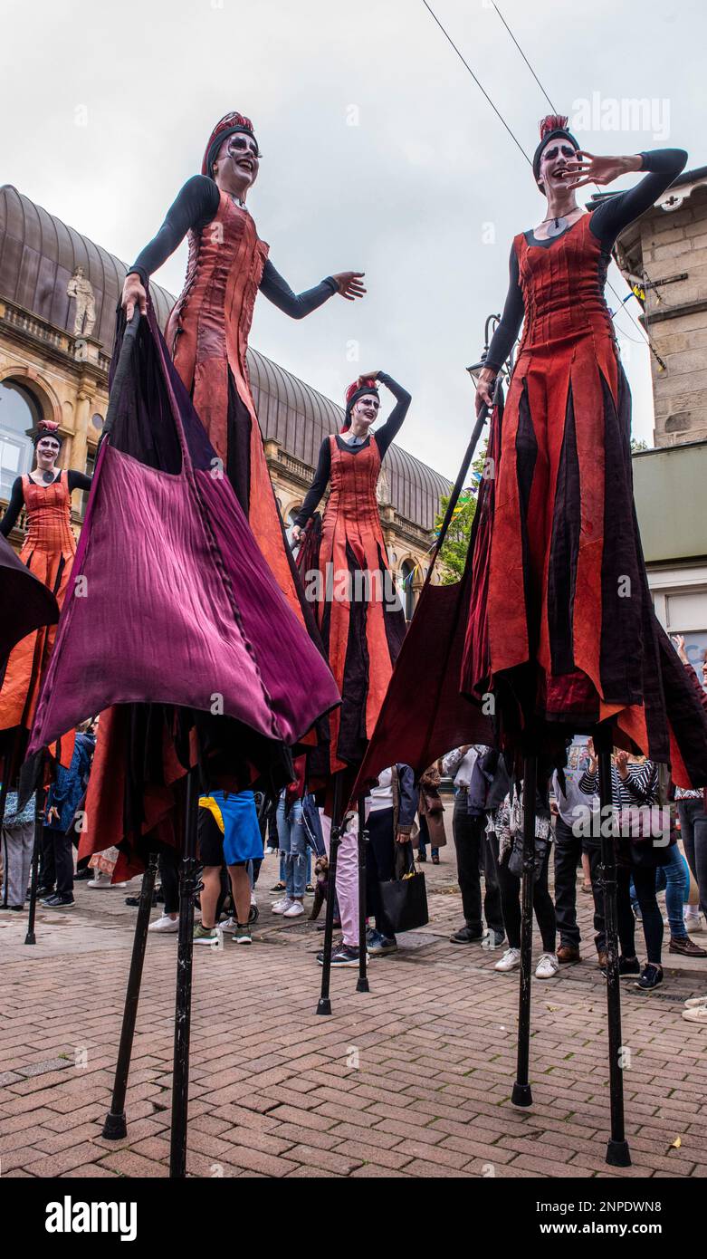 Ladies on stilts holding huge fans parade at the Harrogate Carnival. Stock Photo