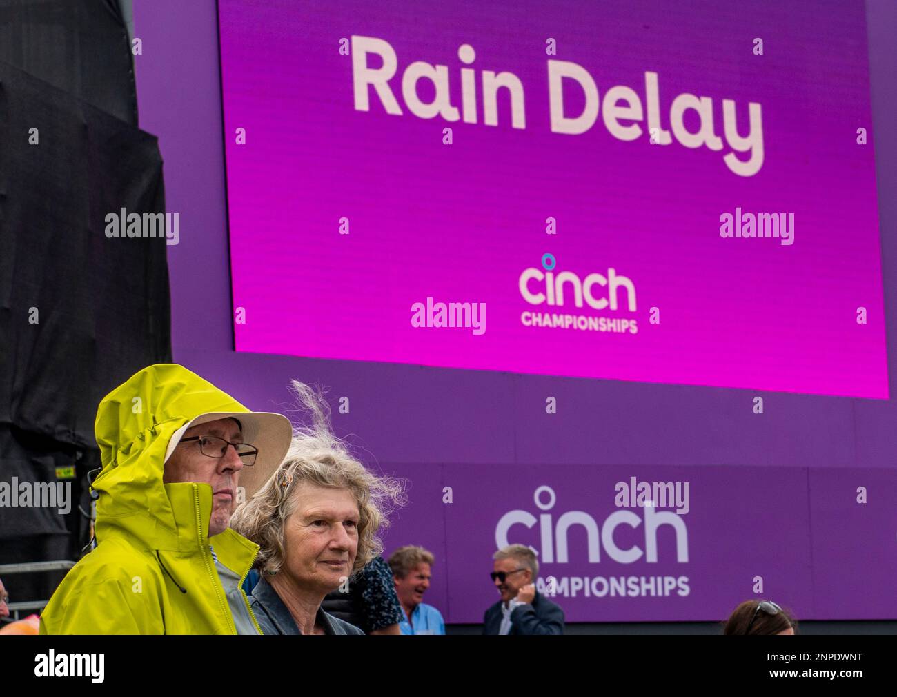 A man and a woman bear the brunt of the bad weather as play is suspended at the Queen's Club tennis tournament. Stock Photo