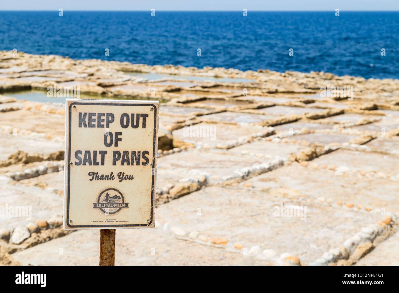 A sign between the road and Xwejni salt pans warning people to keep off the pans where sea salt is harvested. Stock Photo