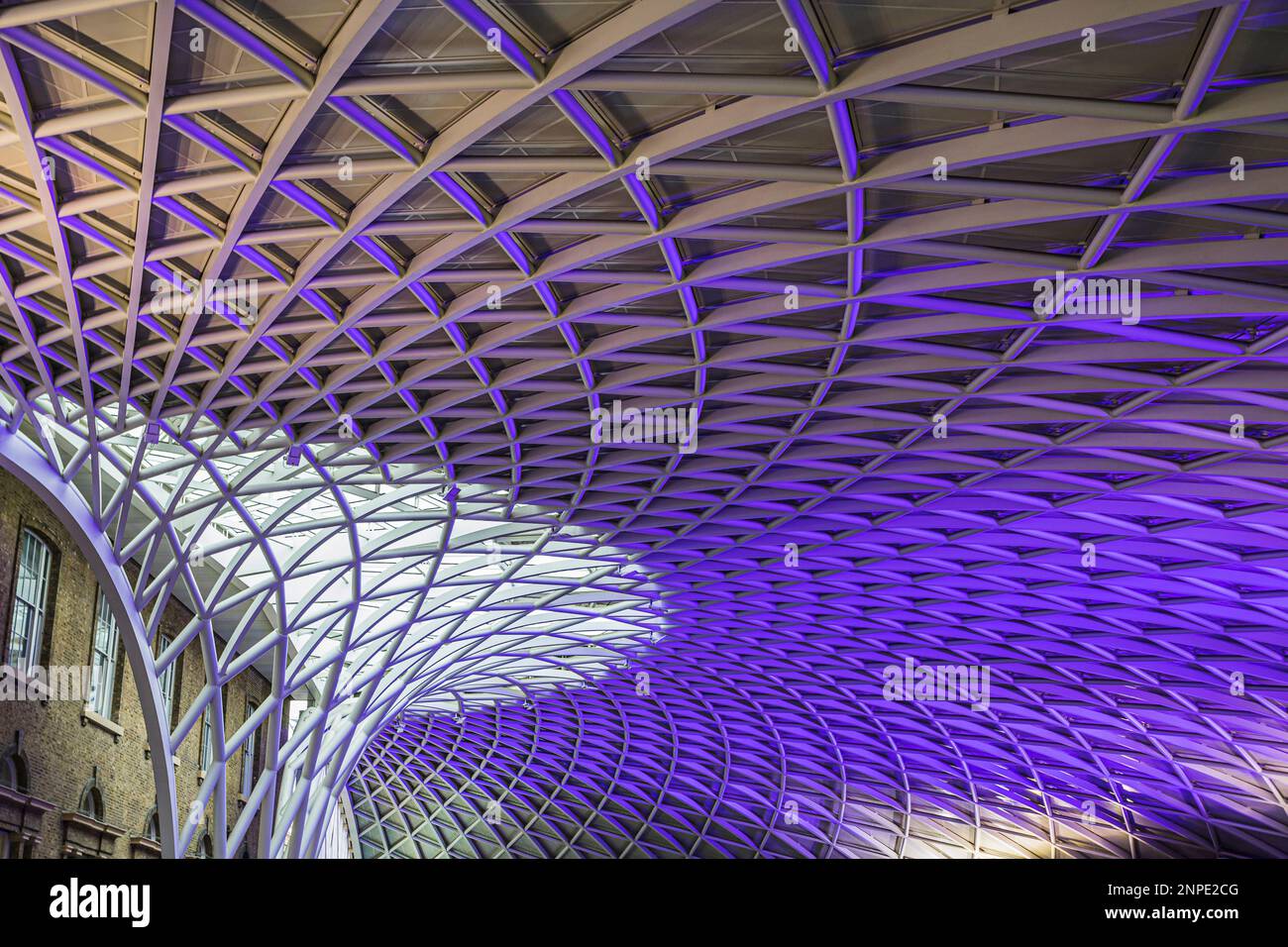 The abstract Kings Cross station ceiling lit up in purple lighting in