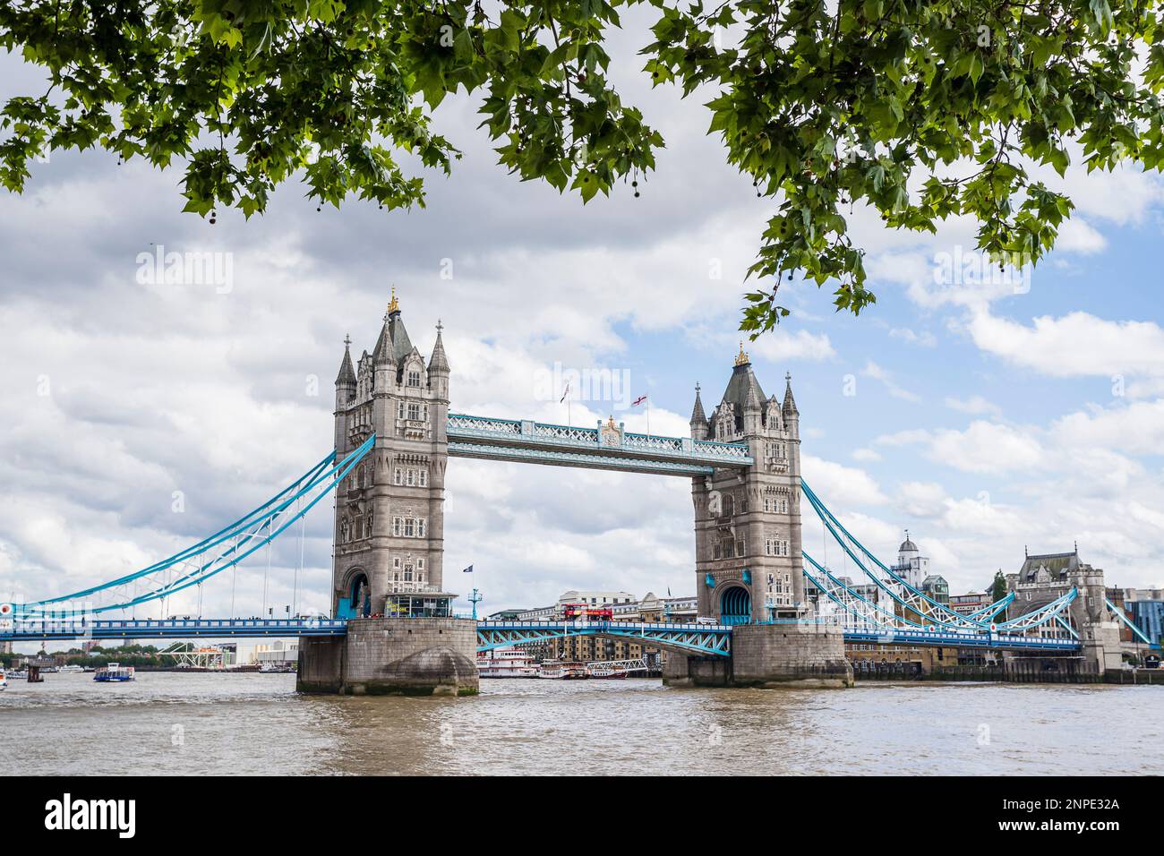 Tower Bridge spanning the River Thames in London seen under a frame of trees from the Northbank . Stock Photo