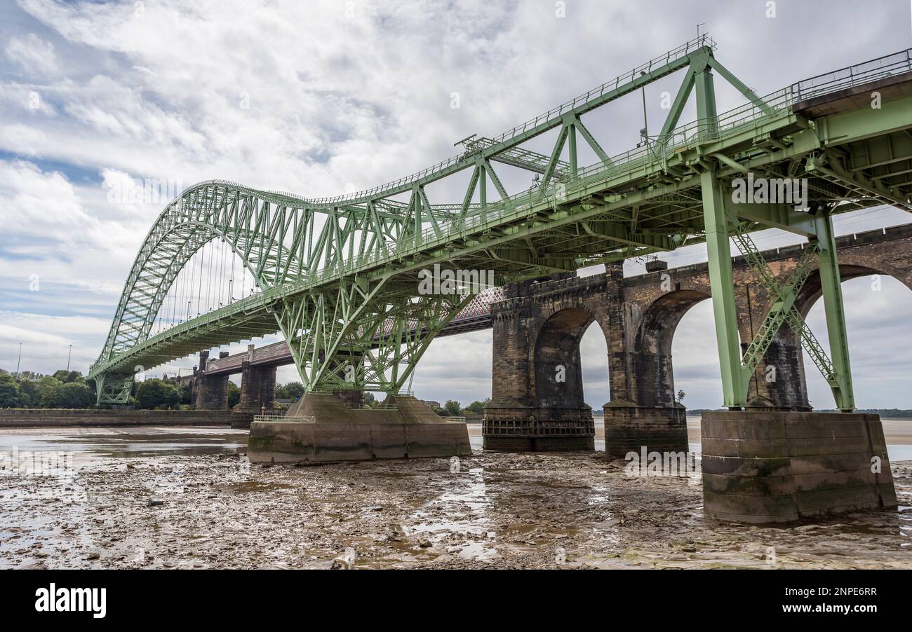 Silver Jubilee Bridge and Runcorn Railway Bridge pictured at low tide from the banks of the River Mersey in Cheshire. Stock Photo