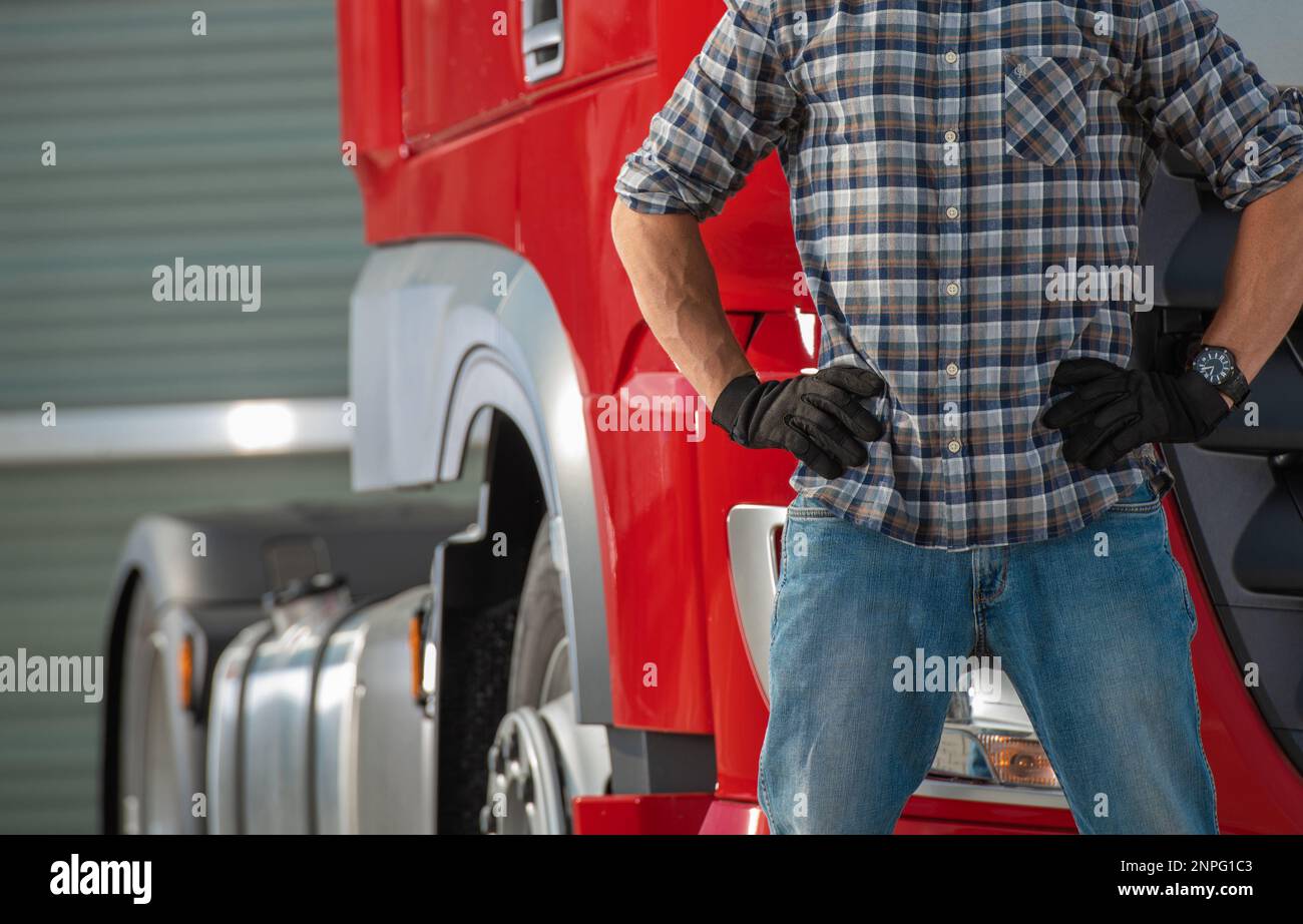 Close Up Of Caucasian Male Truck Driver Standing In Front Of Semi Truck Tractor Close Up. Transportation Theme. Stock Photo