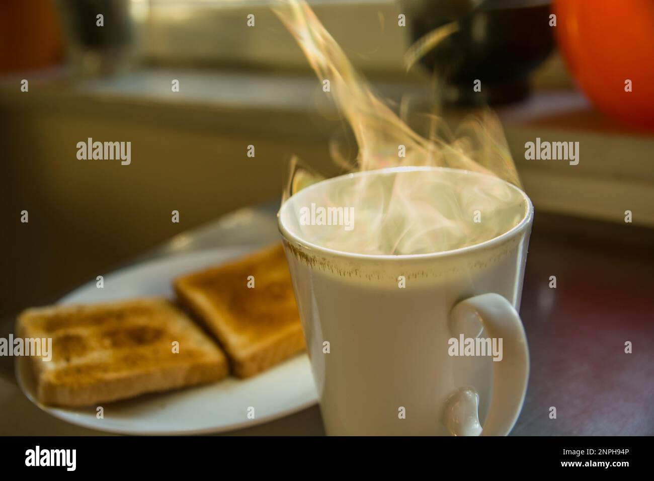 Steam from hot tea and two toasts on a plate, morning view Stock Photo
