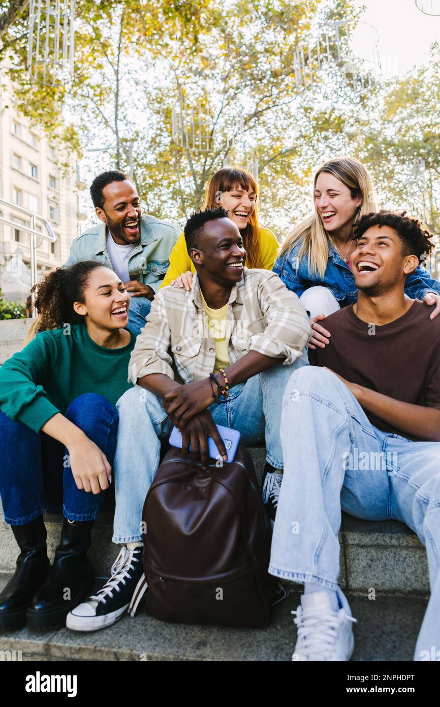 Happy multi-ethnic young diverse hipster student friends hanging out outdoors. Stock Photo