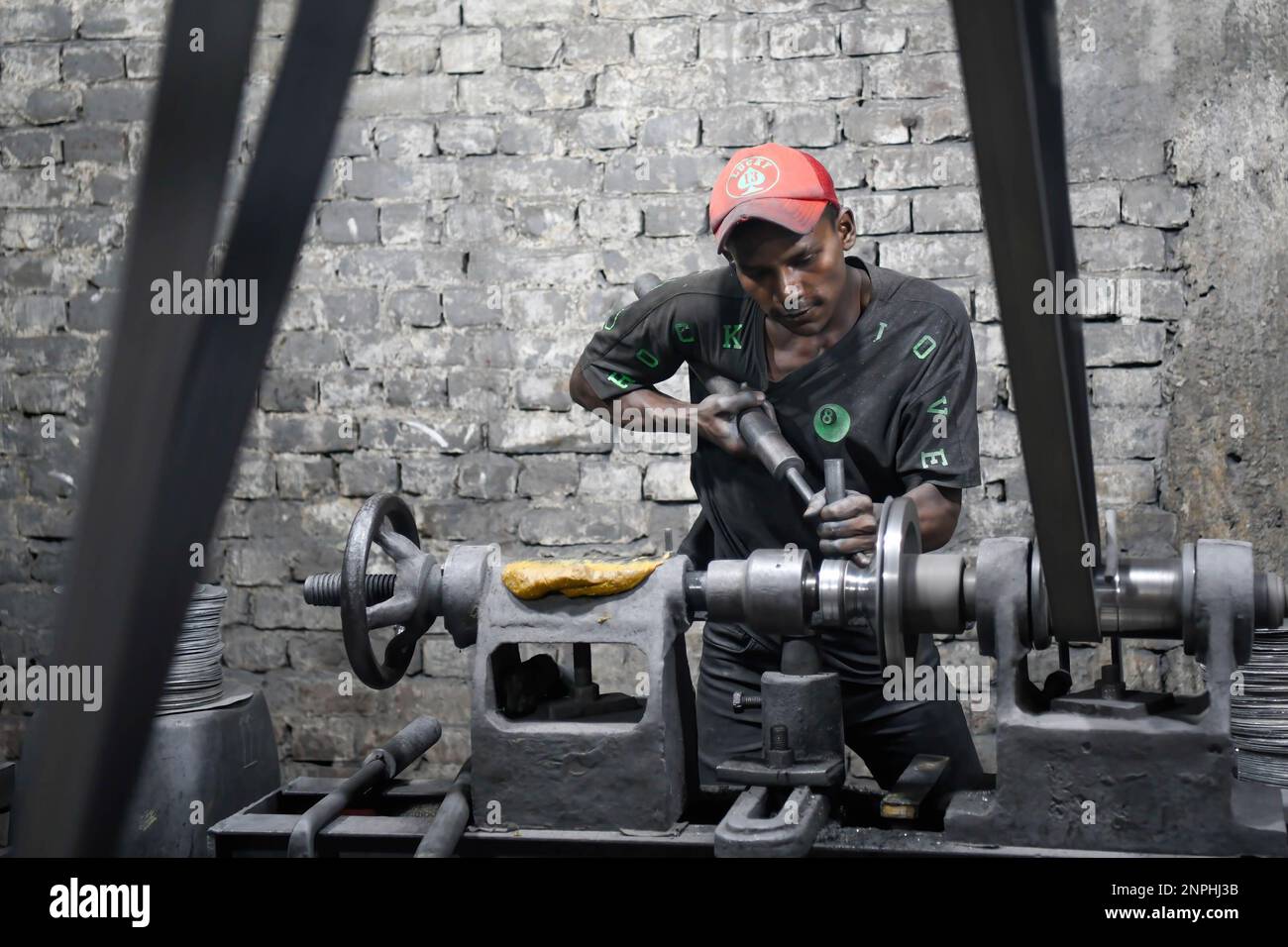 A teenage boy is seen working at a aluminum factory in Dhaka. Aluminum Factory is very common in Bangladesh where different kinds of pot and jar are made from aluminum. Such industry creates a sound source of employment. Among these workers many of them are children aged less than 15 years. Stock Photo
