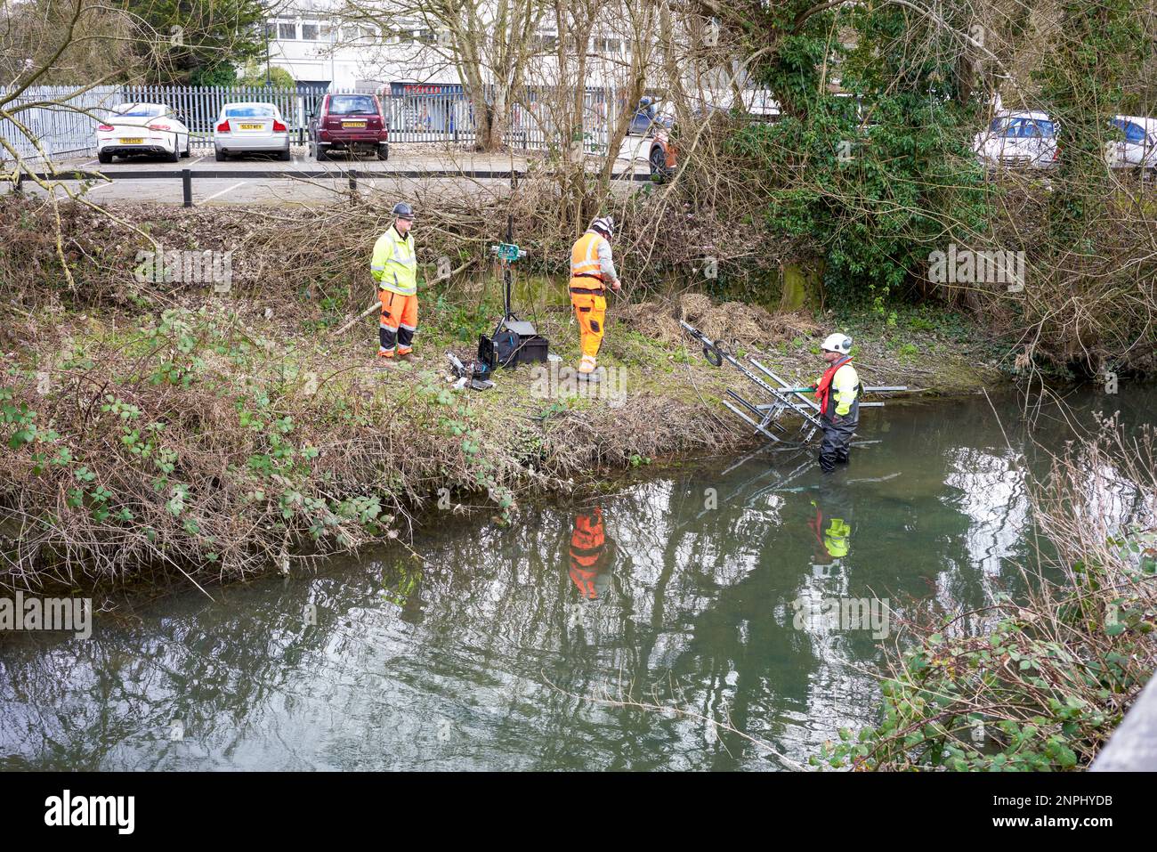 Three men in high visibility clothing working on a silt level monitor on the River Avon as part of the Salisbury water park project Stock Photo