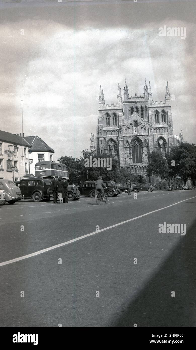 circa 1950s, historical, York, England, UK, showing the large gothic cathedral, known as York Minster. Cars of the era parked and a Double decker bus going to Leeds, with an advertisemen for Barnsley Brewery. Bus driver and female conductor outside chatting with supervisor. Stock Photo