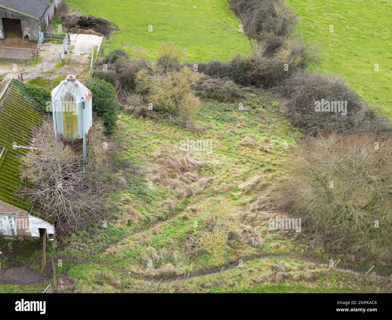 Aerial view of a now derelict dairy farm showing the large metallic grain hopper and some barn sheds. Stock Photo