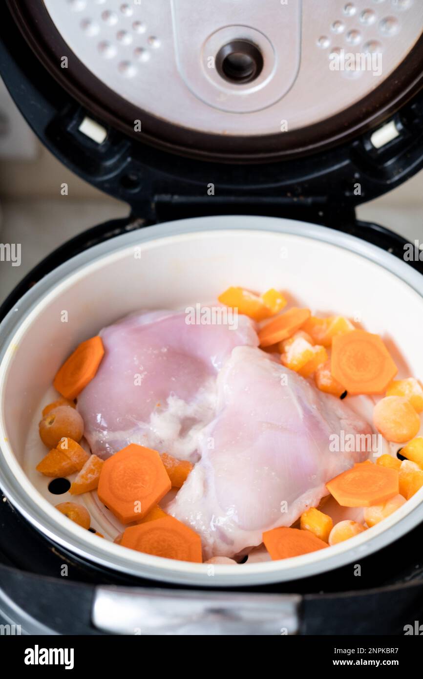 chicken meat and carrot pieces in a double boiler, top view. Steamed meat and vegetables Stock Photo