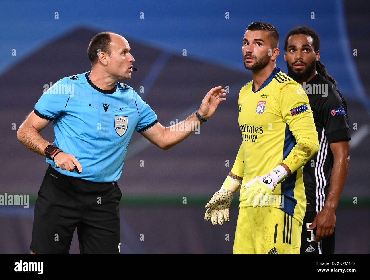 Referee Antonio Mateu Lahoz, left, discusses with Lyon's goalkeeper Anthony  Lopes, centre, and Lyon's Jason Denayer during the Champions League  semifinal soccer match between Lyon and Bayern at the Jose Alvalade stadium