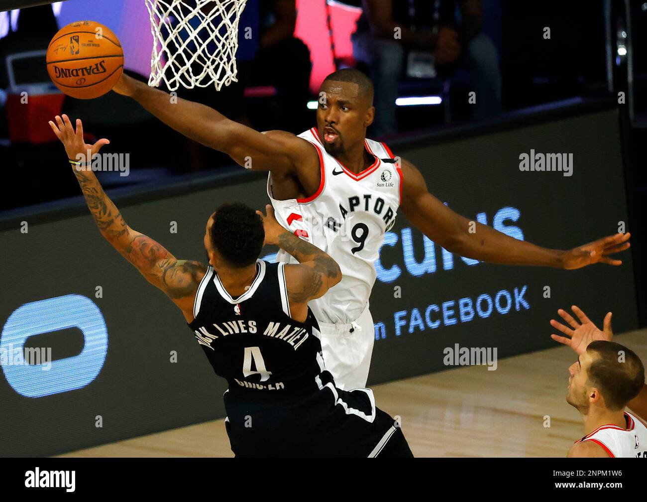Toronto Raptors' Serge Ibaka (9) fouls Brooklyn Nets' Chris Chiozza (4)  during the third quarter in Game Two of an NBA basketball first-round  playoff series, Wednesday, Aug. 19, 2020, in Lake Buena