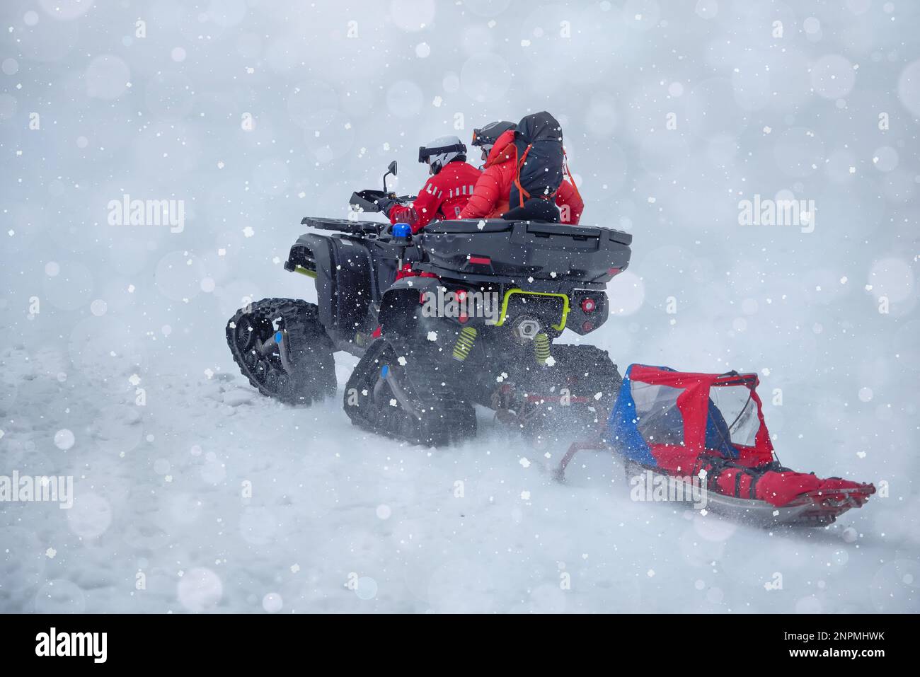 The mountain rescue team is heading out to save a person in the mountains during winter, using a tracked vehicle and a sled Stock Photo
