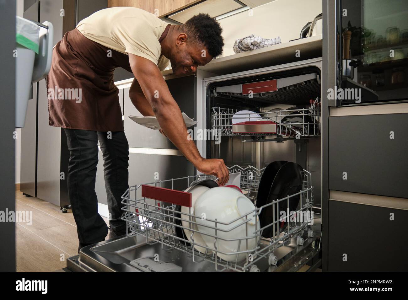 Young black man putting dishes in the dishwasher Stock Photo Alamy