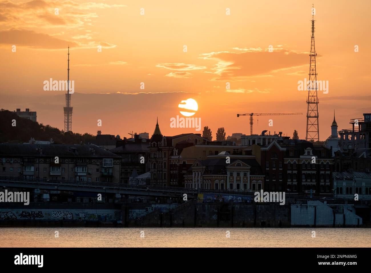 Sunset in Kyiv with a view of Podil downtown district and Dnipro river on the foreground Stock Photo
