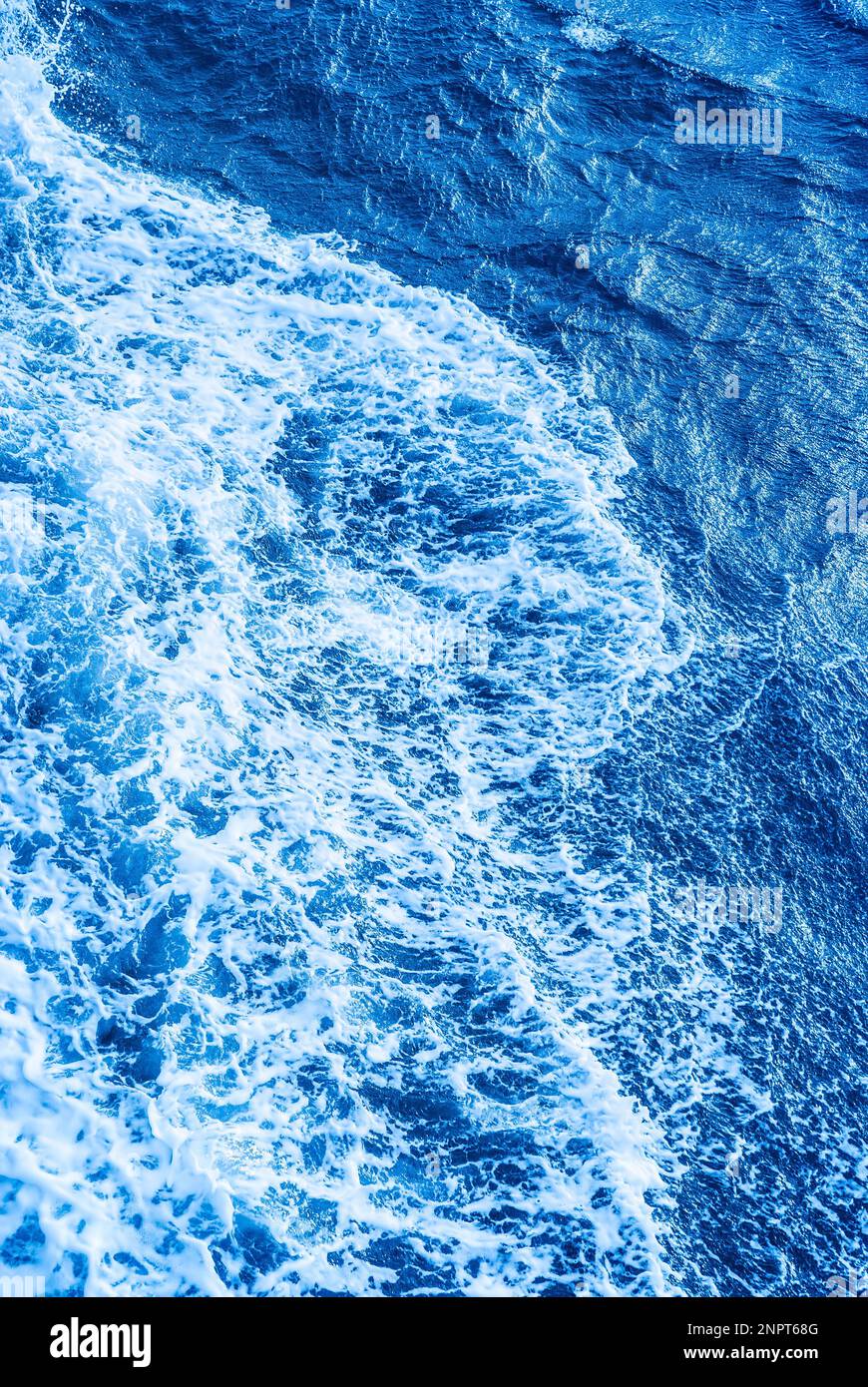 Aerial Ocean water blue surface with foam and waves vertical. Stock Photo