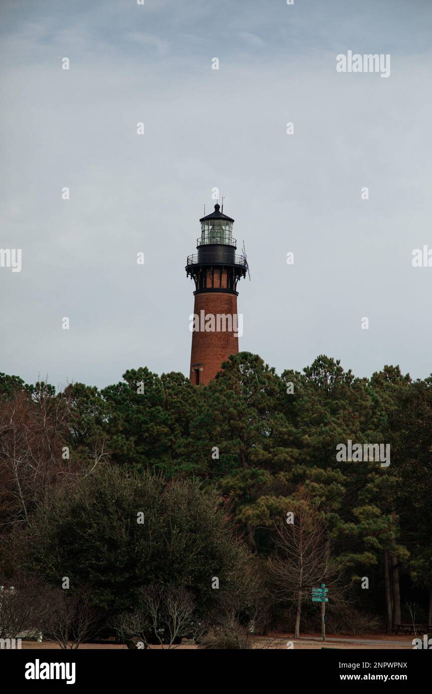Old Brick Lighthouse Overlooking Forest and Dock With Beach Stock Photo