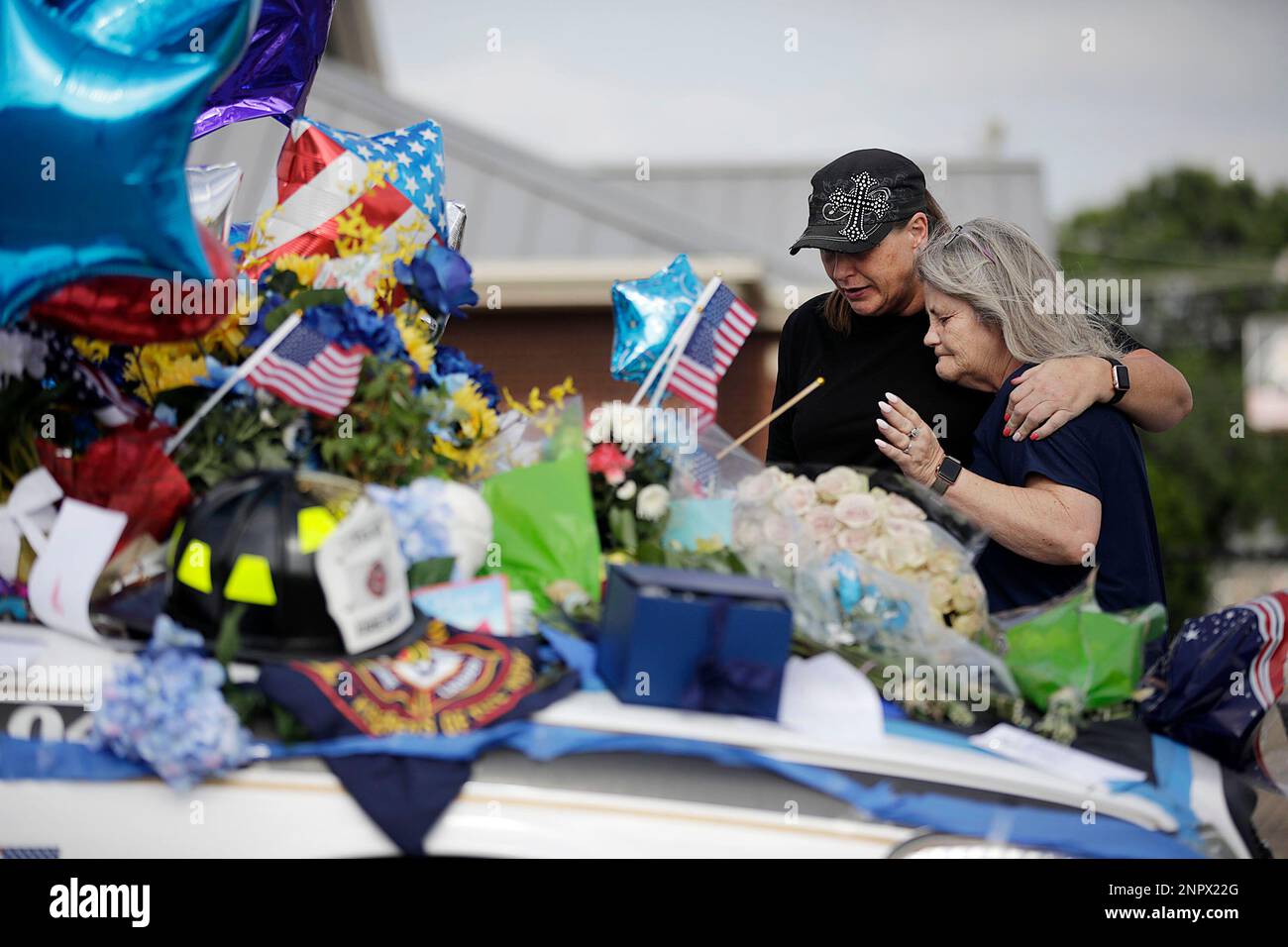 Anna Hok, left, and Terrie Dyer embrace and pray at a makeshift